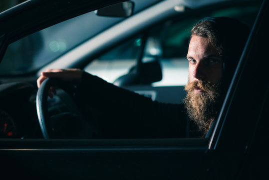 Man with beard and long hair in a car