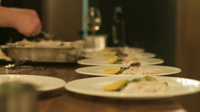 Chef preparing and decorating fish, many round plates&nbsp;with meal in kitchen in restaurant
