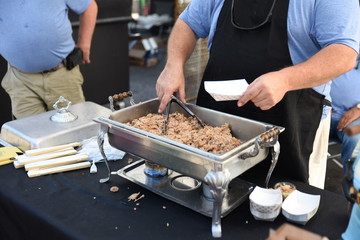 A pitmaster serves pork barbeque samples during a competition in downtown Raleigh