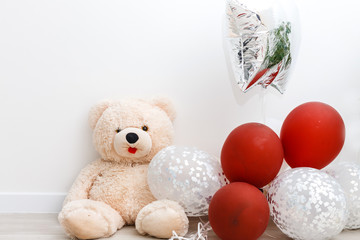 Teddy bear with colorful balloons isolated on white