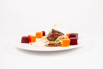 Beef cheeks with vegetables, roasted parsley root mousse , pearl barley, dark chocolate and demi glace sauce on a white background