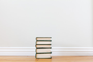 a stack of five books on the floor in a bright room