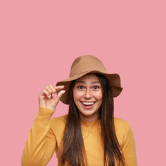 So small. Glad young hipster shapes tiny object with finger, smiles gladfully, being in good mood, dressed in fashionable outfit, poses over pink background, free space above, unimpressed with amount