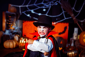 Portrait of a boy dressed in a costume of a vampire over grunge background. Halloween party.