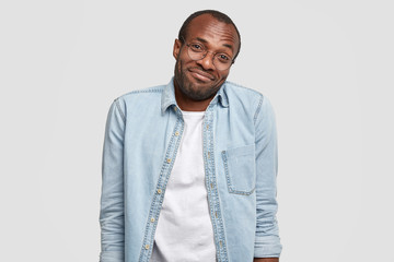 Insecure hesitating stressed black man looks clueless at camera, shrugs shoulders, recieves good...