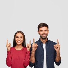 Happy brother and sister smile broadly, attract your attention upwards, suggest or advice go...