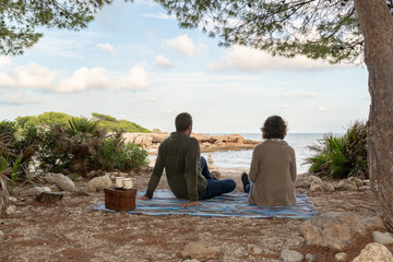 Pajera haciendo un picnic romántico en una playa mediterránea durante un otoñal atardecer.  Concepto de tranquilidad.