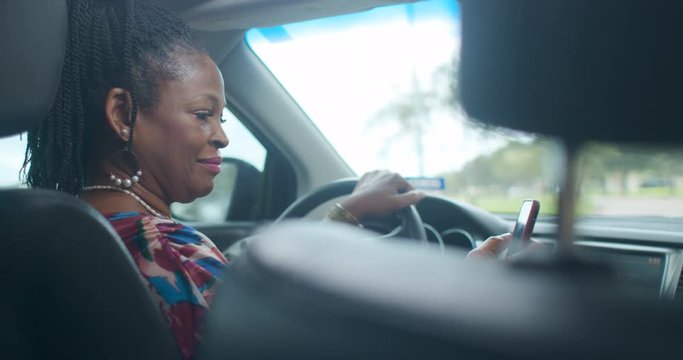 An Uber of Lyft type driver checks the ride sharing app on her smart phone to verify the assignment then engages passenger in friendly conversation.
