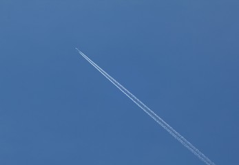 Plane flying on a blue sky, condensation line.