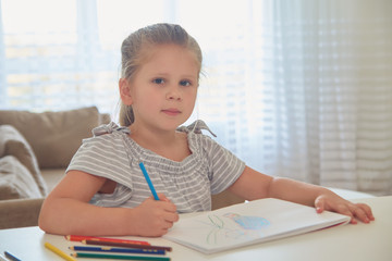 Little girl drawing with pencils at home