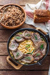 Beef tongue in cast iron skillet with cream sauce, rustic style.