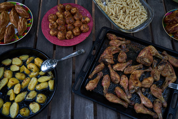 Table with variety food top view. Party snack food table with baked potatoes, fried chicken drumsticks, italian pasta and puff pastry buns bread, close-up