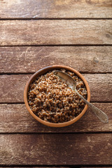 Bowl with cooked buckwheat on old wooden background, copy space.