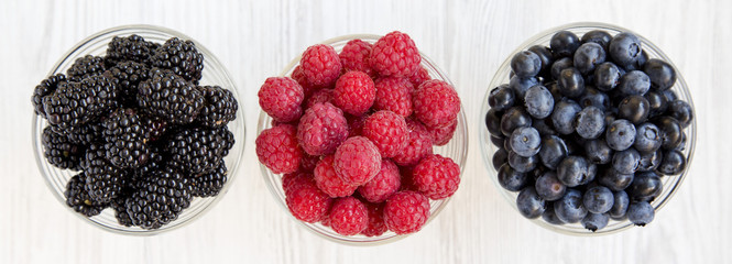 Full bowls containing berries: blueberries, blackberries, raspberries. Healthy eating and dieting. From above, overhead, top view.