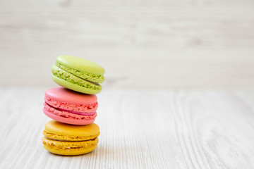 Stack of colorful macaroons on a white wooden background, side view. Copy space.