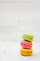 Stack of colorful macarons on a white wooden background, side view. Copy space.