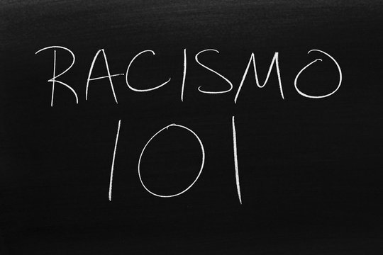 The words Racismo 101 on a blackboard in chalk.  Translation: Racism 101