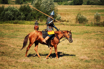 Medieval armored equestrian soldiers with lances on horses