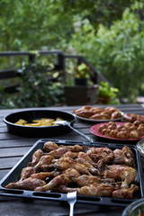 Party snack food table with baked potatoes, fried chicken drumsticks, italian pasta and puff pastry buns bread, close-up. Table with variety food top view. 