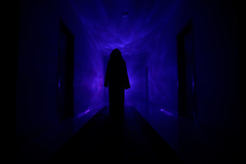Creepy silhouette in the dark abandoned building. Dark corridor with cabinet doors and lights with...