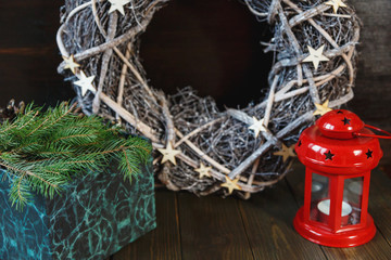 red lantern , green box with branches of fir tree and christmas wreath on the wooden background. New year and christmas home decor, celebration concept