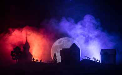 Fototapeta na wymiar Scary view of zombies at cemetery dead tree, moon, church and spooky cloudy sky with fog, Horror Halloween concept.