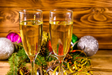 Two wineglasses with champagne and different christmas decorations on wooden table