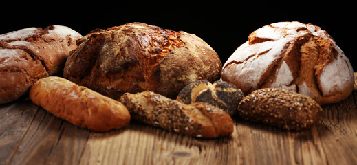 Different kinds of bread and bread rolls on board from above. Kitchen or bakery