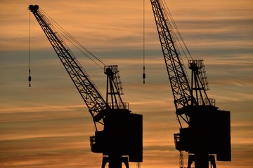 Fototapeta premium Harbour cranes, Jersey, U.K. Dramatic Autumn sunset over industry.