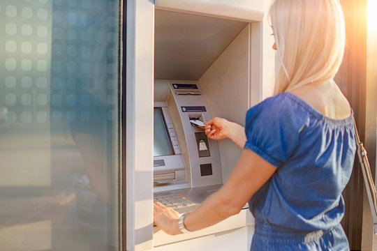 Young Woman Withdrawing Money From Credit Card At ATM Machine