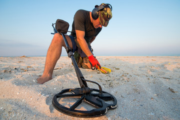 Man with a metal detector on a sea sandy beach - 225098744