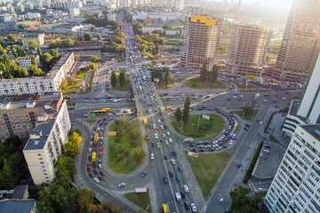 Aerial drone view of two level road junction during rush hour. Traffic jam in busy urban highway with circles. Busy street with lot of cars at Kiev, capital of Ukraine. Sunset golden hour flare