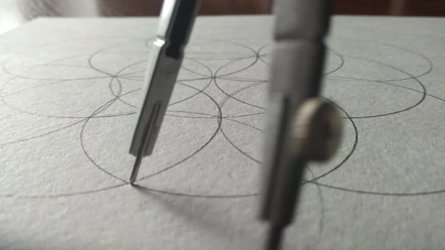 The compasses draw a circle on a piece of paper