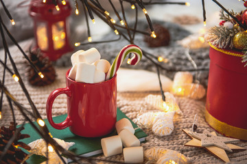 Close up mug of cocoa with marshmallow and candy situating on copybook. Celebration concept