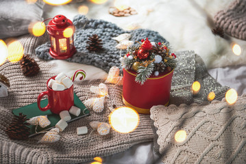 Beautiful present box with branches of artificial tree situating near mug with marshmallow and sketch-book. Christmas concept