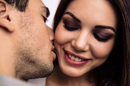 Couple. Passion. Love. Close-up of man kissing a woman in cheek, she is smiling