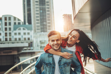 Portrait of outgoing woman gesticulating hand while hugging smiling male during rest outside. They...