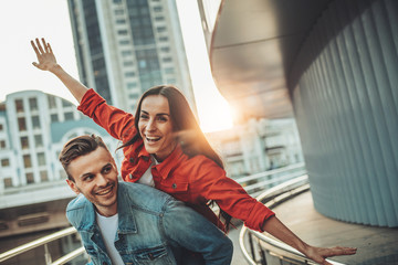 Portrait of cheerful man having fun with positive girl while imitating plane with arms outdoor. Glad couple having fun together concept © Yakobchuk Olena
