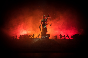 War - no justice concept. Military silhouettes fighting scene and The Statue of Justice on a dark toned foggy background.