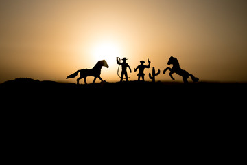 Fototapeta na wymiar Cowboy concept. Silhouette of Cowboys at sunset time. Cowboys silhouettes on a hill with horses.