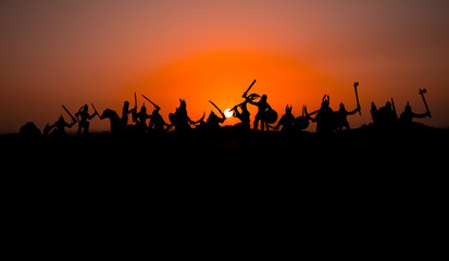 Fototapeta na wymiar Medieval battle scene with cavalry and infantry. Silhouettes of figures as separate objects, fight between warriors on sunset foggy background.