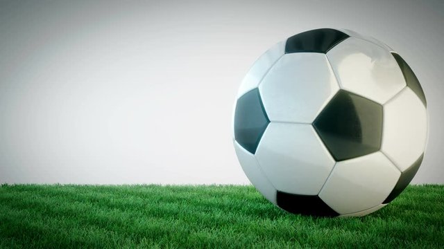 Rotating glossy soccer ball on grass field - seamless loop