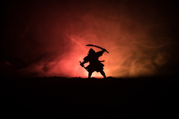 Fighter with a sword silhouette a sky ninja. Samurai on top of mountain with dark toned foggy...