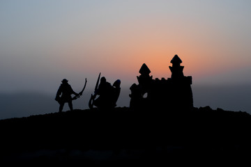 Medieval battle scene on sunset. Silhouettes of fighting warriors on sunset background.