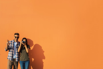 Portrait of outgoing male gesticulating hands while standing near smiling girl with digital device in hands. Copy space