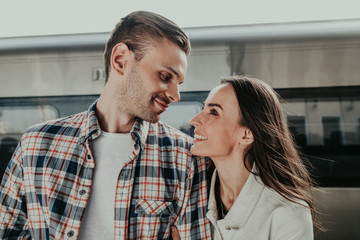 Side view cheerful man taking with pleased beaming girlfriend before trip outside. Optimistic couple during conversation concept