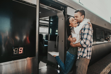 I am so glad to see you. Outgoing lady hugging cheerful man from train. Meeting of two lovers concept