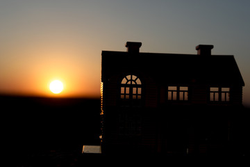 decorative small metallic house on the sunset background. Selective focus