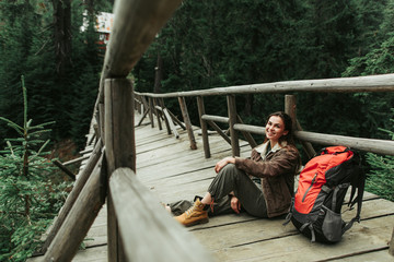 Magic forest. Portrait of beautiful girl resting on bridge on the way to the camp. She is looking at camera with happy smile