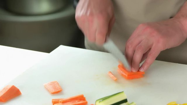 Hands cutting fresh carrot. Chef using knife close up.
